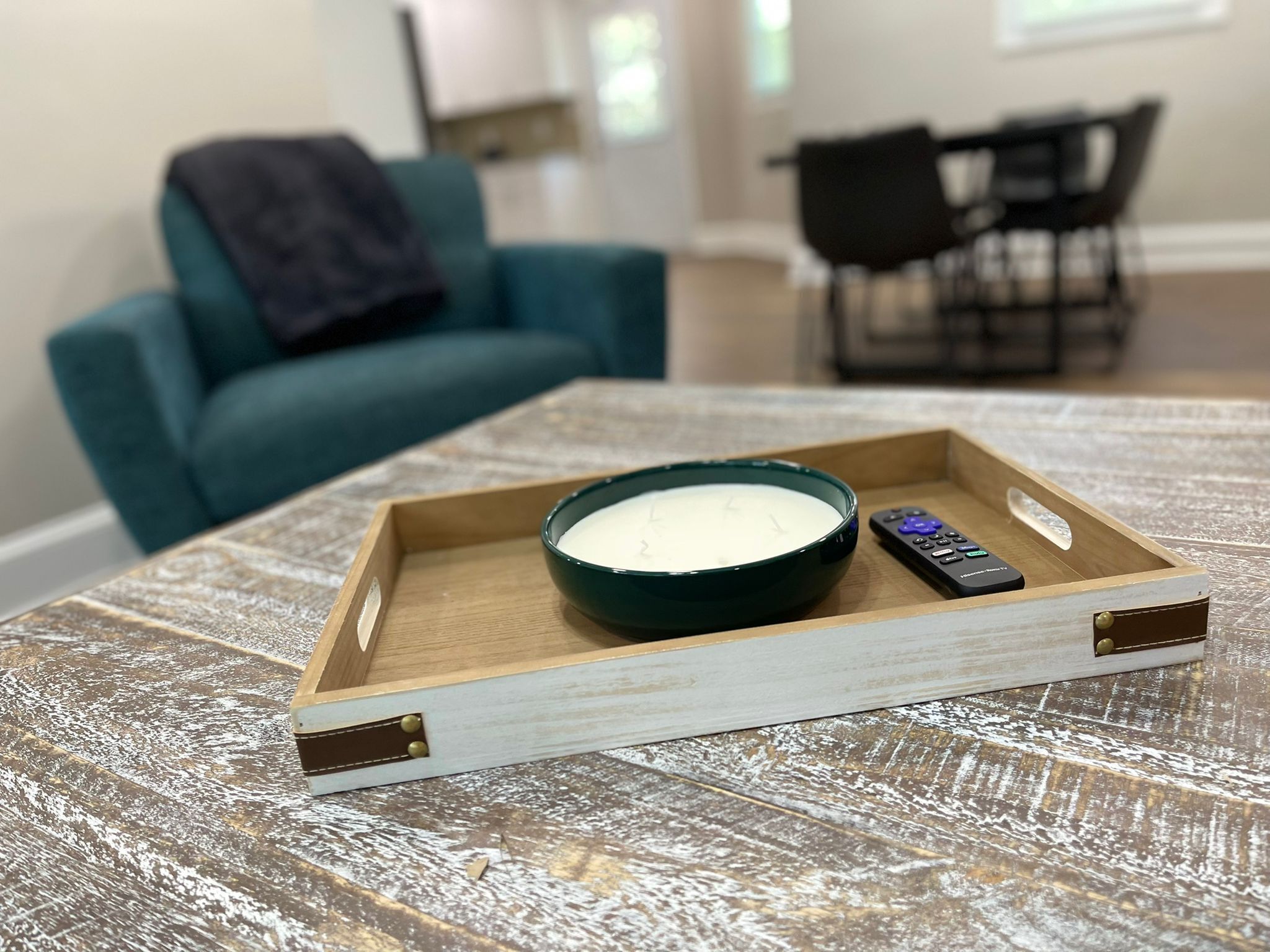 Un plateau en bois sur lequel se trouve un bol contenant une substance blanche et une télécommande, le tout posé sur une table à surface texturée.
