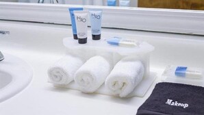 A bathroom with a white sink, two H2O branded bottles, three rolled towels, and a black towel with 'Makeup' written on it. - Queen Bed Standard View (Fairhaven)