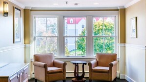 A room with two chairs, a small table, and large windows with a view of buildings and trees. - Lincoln NH | Ski Town Stay | Pool & Mountain Access (Lincoln)