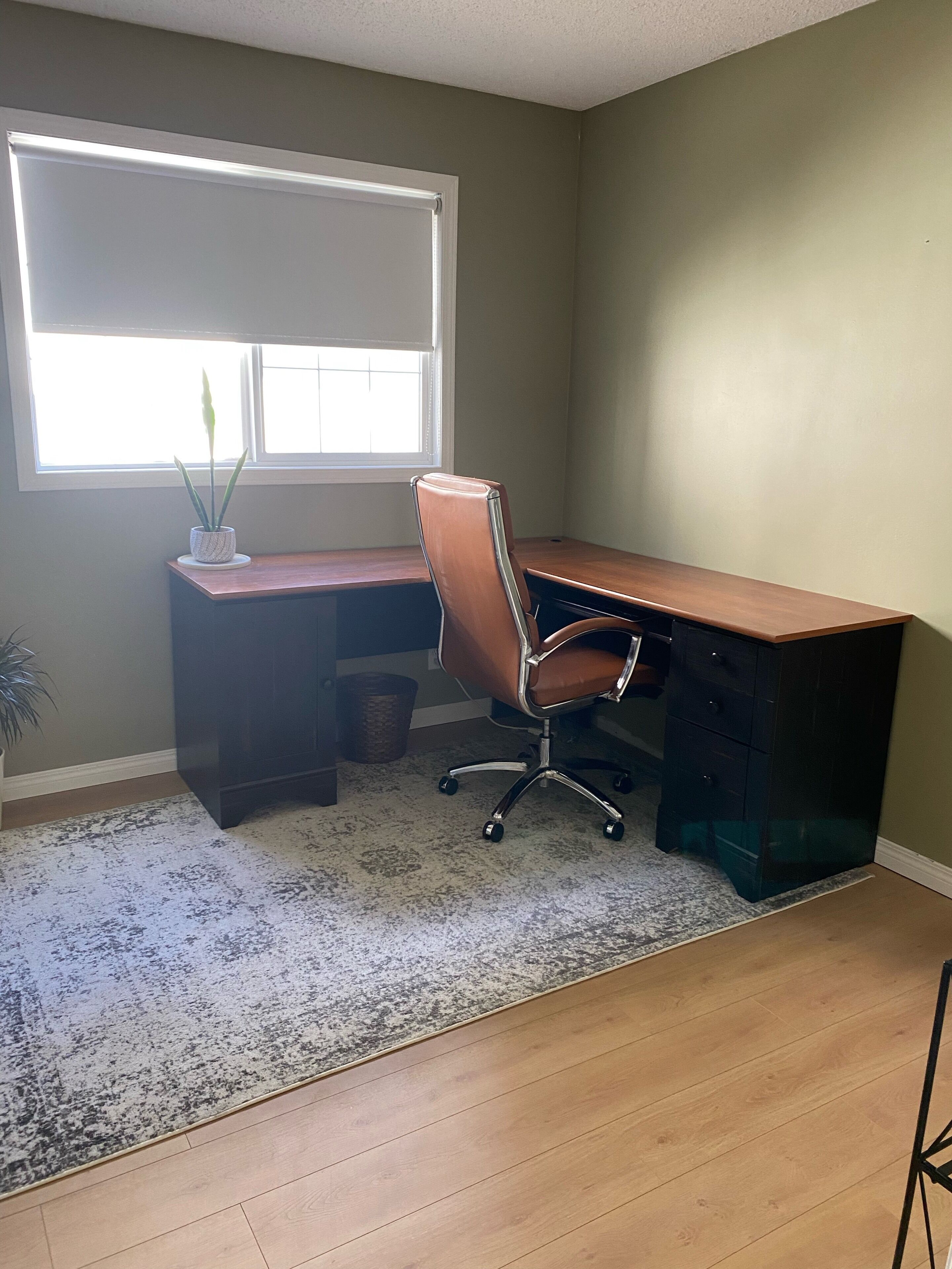 A home office with a desk, chair, and a window with blinds.