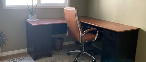 A home office with a desk, chair, and a window with blinds.