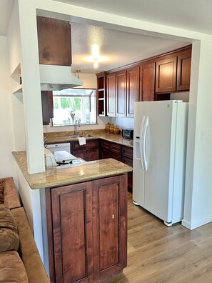 A kitchen with wooden cabinets, a white refrigerator, and a granite countertop.