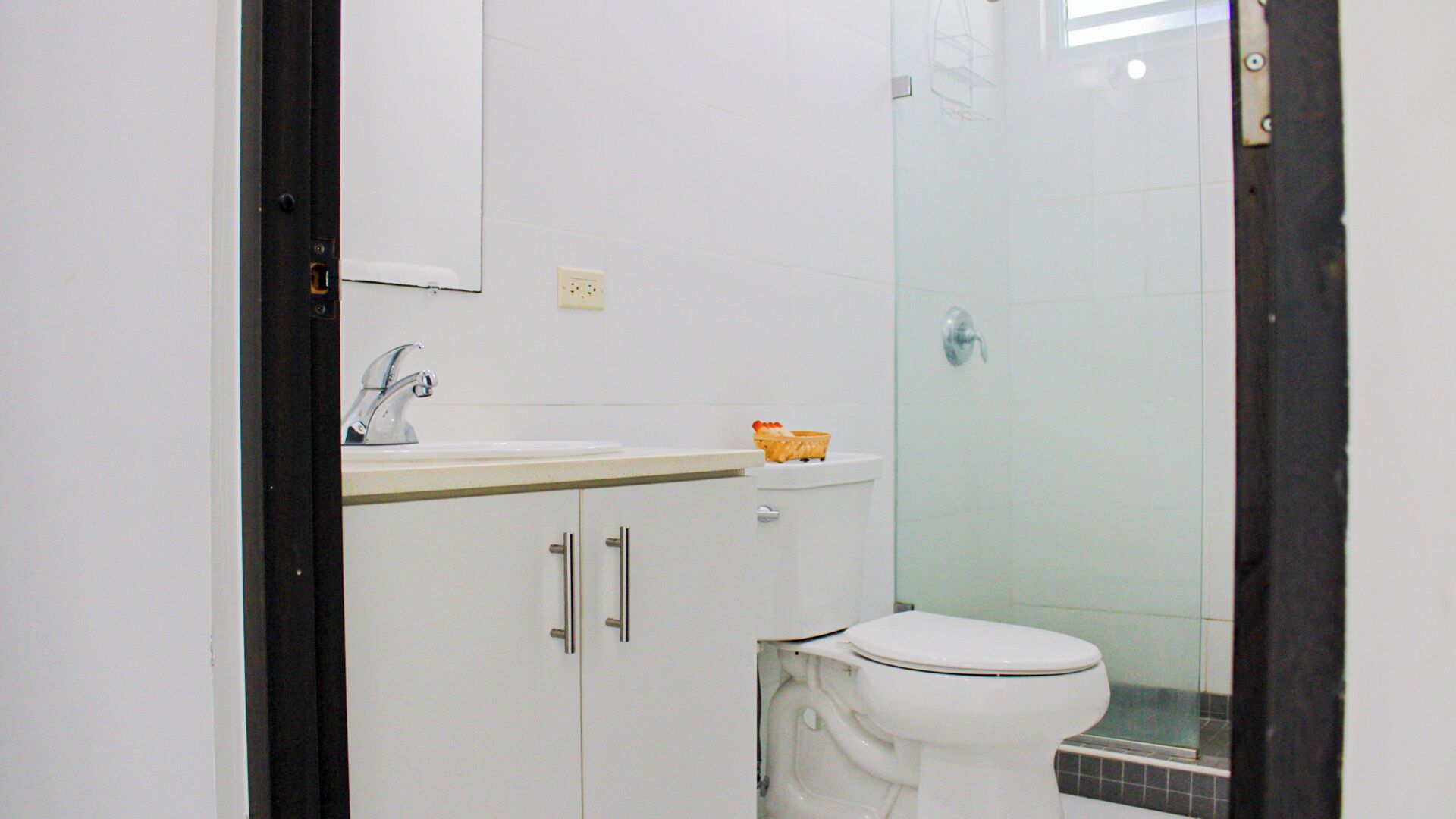 A bathroom with a white sink, a toilet, and a glass shower enclosure.
