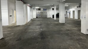 A parking garage with concrete floors and white walls, featuring multiple parking spaces and columns. - Arecibo Hotel 2104 (Arecibo)
