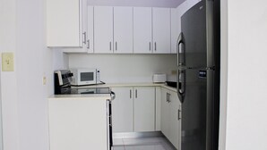 A compact kitchen with white cabinets, a stainless steel refrigerator, a microwave, and a toaster. - Arecibo Hotel 2104 (Arecibo)