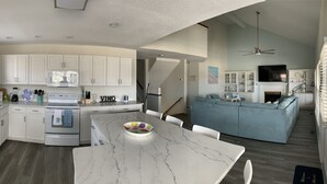 A spacious kitchen with white cabinets, a marble island, and a dining area. - Canal House, New Bar/TV Area w/ view of water, Fenced yard & 5 Min Walk To Beach (Ocean Isle Beach)