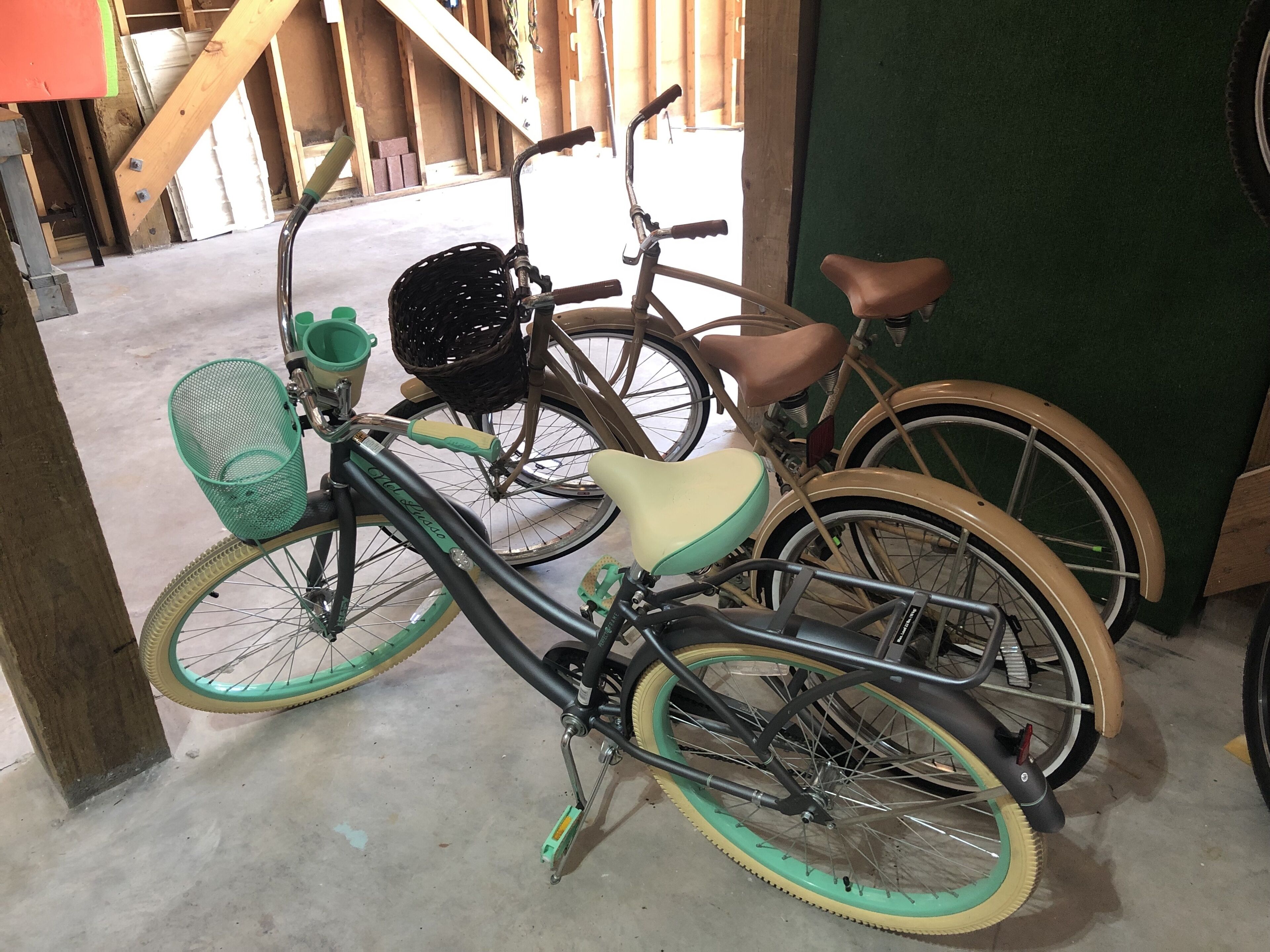 Ein Fahrrad mit Korb und grünem Sattel, das an einer Wand angelehnt ist.