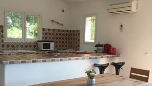 A kitchen with a tiled backsplash, a microwave, a red toaster, and a window with a view of greenery. - Comfortable villa with private pool 5 minutes from the beach (zonza)