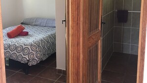 A room with a bed, a wooden door, and a bathroom with tiled walls and a shower. - Comfortable villa with private pool 5 minutes from the beach (zonza)