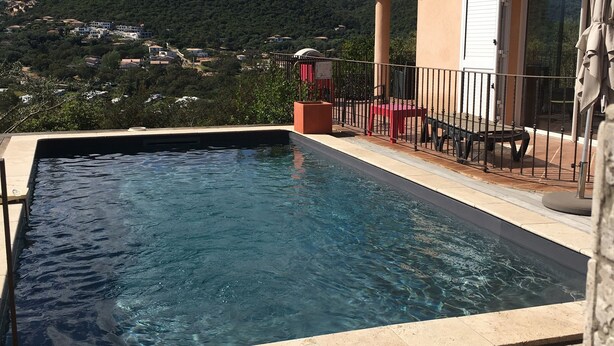A swimming pool with a wooden deck, a covered seating area, and a mountain view in the background. - Comfortable villa with private pool 5 minutes from the beach (zonza)