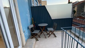 En balkong med en blå vägg, en vit dörr och ett litet bord med två stolar.