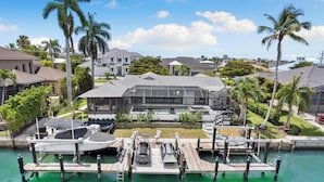 A marina with boats docked, a covered seating area, and a large building with a sloped roof. - Island Retreat .6 miles from the beach! (Marco Island)