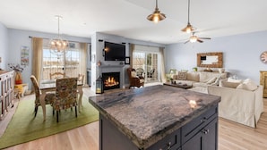 A spacious living area with a fireplace, a large island, and a dining area with chairs.