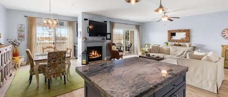 A spacious living area with a fireplace, a large island, and a dining area with chairs.