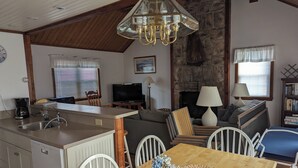A cozy living space with a kitchen, dining area, and a fireplace. - Private cottage in Madaket just a 10 min walk or short drive to the beach. (Nantucket)