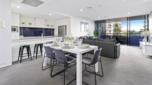 Un appartement moderne comprenant un coin repas, une cuisine et un espace de vie avec balcon.
