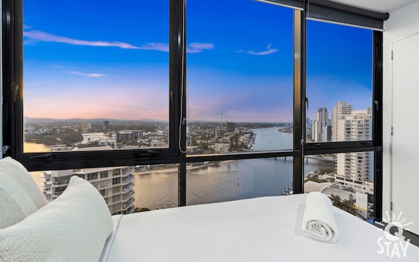 Enjoy a panoramic city view from the comfort of your room, featuring a large window and a neatly made bed.