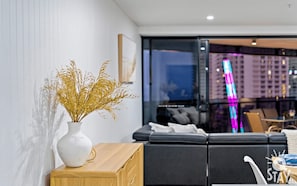 Relax in a stylish living room with a black leather sofa and city views through a glass partition.