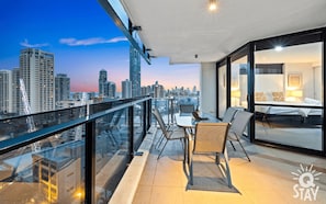Enjoy a panoramic city view from the balcony, featuring a large bed and seating area.