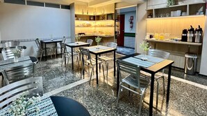 A modern dining area with tables and chairs, a kitchen area with shelves and appliances, and a tiled floor. - HOTEL BURITI STOP (Aparecida de Goiania)