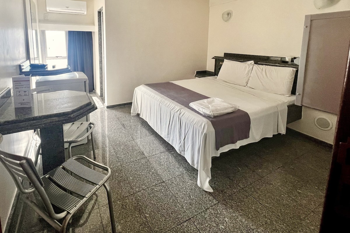 A hotel room with a bed, a desk, and a chair.