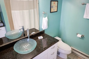 A bathroom with a glass bowl sink, a white toilet, and a towel rack. - Deluxe Suite standard room (Fairhaven)