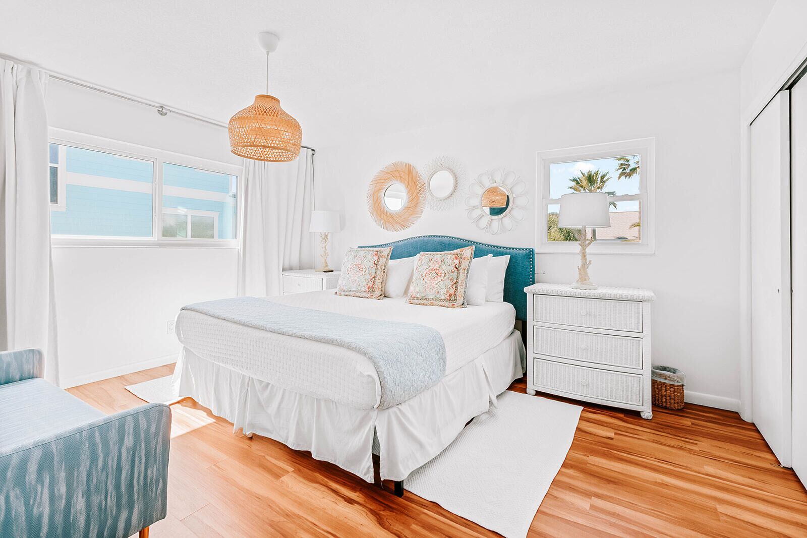 Un dormitorio con cama, mesitas de noche, cómoda, lámpara colgante y ventana con vistas.