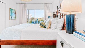 A bedroom with a bed, bedside lamps, a nightstand, and a view of the outside.