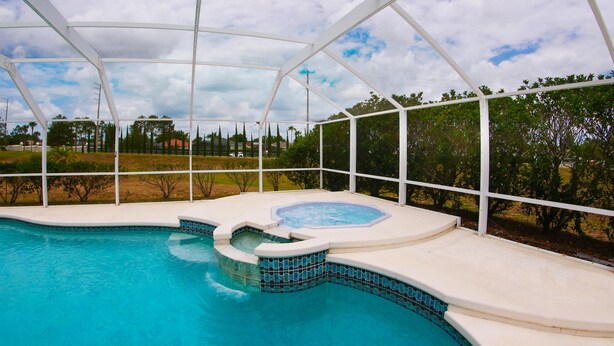 Piscina interna com hidromassagem, cercada por área coberta e vista para um bairro residencial.