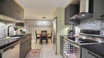 A modern kitchen with a dining area, stainless steel appliances, and a hexagonal tile backsplash.