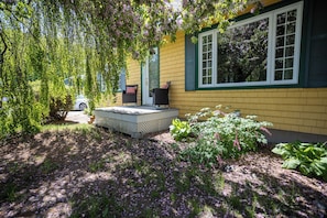 A yellow house with a porch, a bench, and a car parked outside. - Aubergélit (Saint Jean Port Joli)