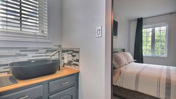 Une salle de bain moderne avec un grand lavabo noir sur pied, un miroir et un mur recouvert de carreaux.