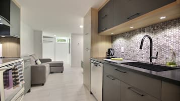 A modern kitchen with a built-in dishwasher, a coffee machine, and a sink with a black faucet.