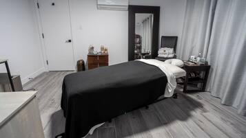 Relax in a serene space with a neatly made bed, wooden floor, and a stylish nightstand.