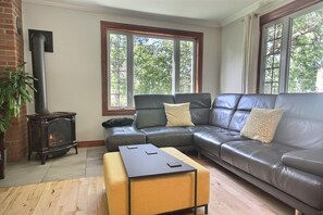 A living room with a fireplace, leather sofa, and a coffee table. - Aubergélit (Saint Jean Port Joli)