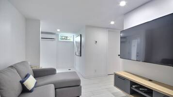 A modern living room with a grey sofa, a flat-screen TV, and a minimalist design.