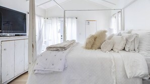 Ein hell eingerichtetes Schlafzimmer mit Bett, Fernseher und Tür.