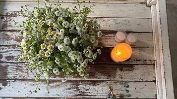 Una superficie de madera rústica con un arreglo floral y dos velas encendidas.