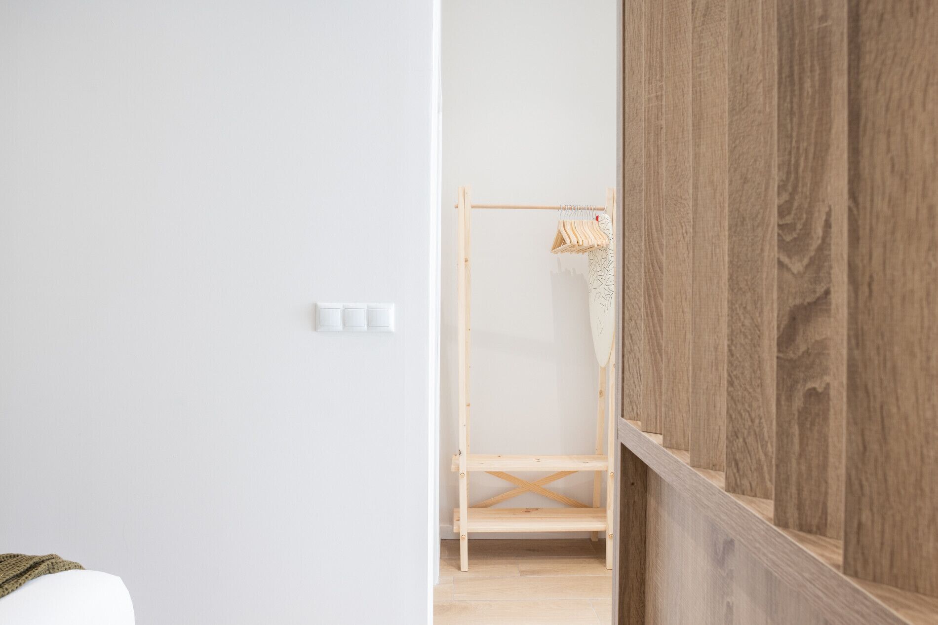 Une pièce au décor minimaliste, avec une armoire en bois, un mur blanc et une étagère en bois.