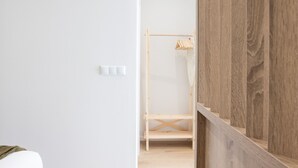 A minimalist room with a wooden wardrobe, a white wall, and a wooden shelf unit. - The Sea Rooms VIII | AC & WIFI | 15 min Beach (Valencia)