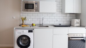 A compact kitchen with a washing machine, a microwave, and a dishwasher. - The Sea Rooms VIII | AC & WIFI | 15 min Beach (Valencia)