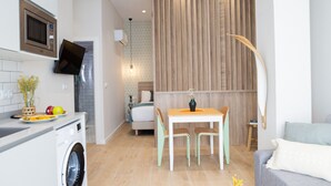 Une cuisine compacte équipée d’un four à micro-ondes, d’un lave-linge et d’un coin repas avec une table et des chaises.