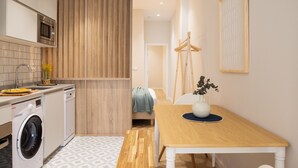 Una cocina compacta con lavadora, microondas y un revestimiento de panel de madera.