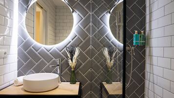 Un baño moderno con un espejo redondo, un lavamanos blanco y plantas decorativas.