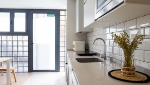 A modern kitchen with white tiles, a sink, a toaster, and a door marked "SALIDA".