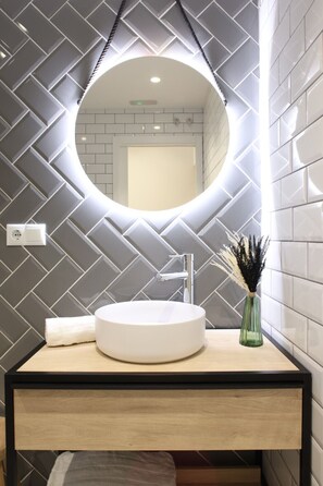 A modern bathroom with a round mirror, white sink, and a decorative vase. - The Sea Rooms XI | AC & WIFI | 15 min Beach (Valencia)