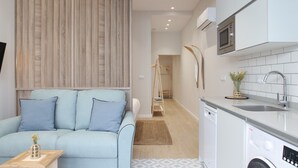 A modern kitchen with white cabinets, a built-in microwave, and a stainless steel sink.