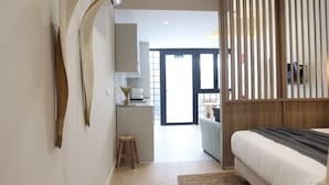 Habitación de hotel moderna con cama, panel de madera, zona de cocina y vistas al exterior.