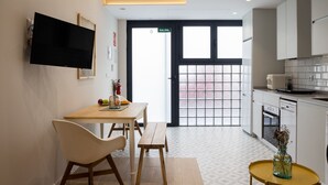 Een moderne keuken met een eethoek, een aan de muur bevestigde televisie en een deur met de aanduiding 'SALIDA'.