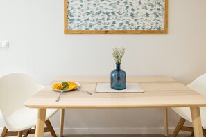 Ein Esstisch mit einer blauen Blumenvase, einem Teller mit Orangenscheiben und einer Gabel.